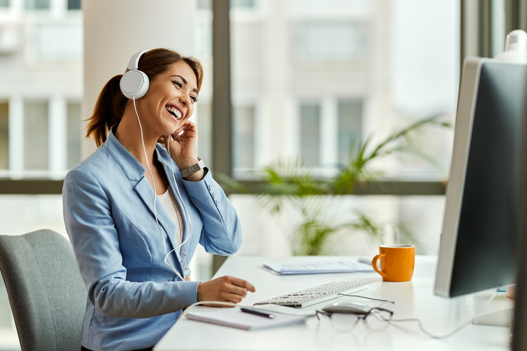 young-businesswoman-having-fun-listening-music-headphones-while-working-computer-office